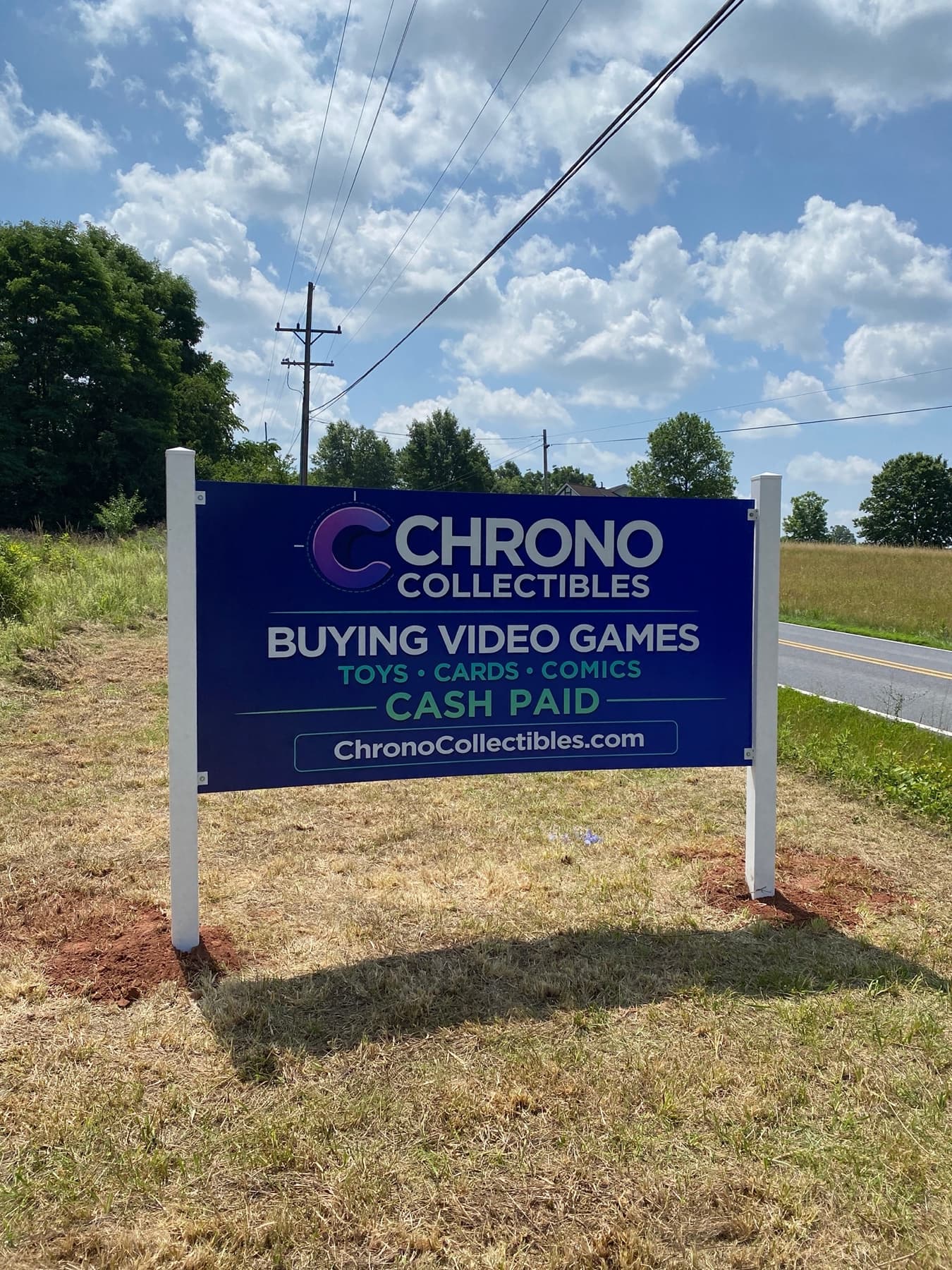 The Chrono Collectibles roadside sign standing in a field — Buying Video Games, Toys, Cards & Comics, Cash Paid, ChronoCollectibles.com